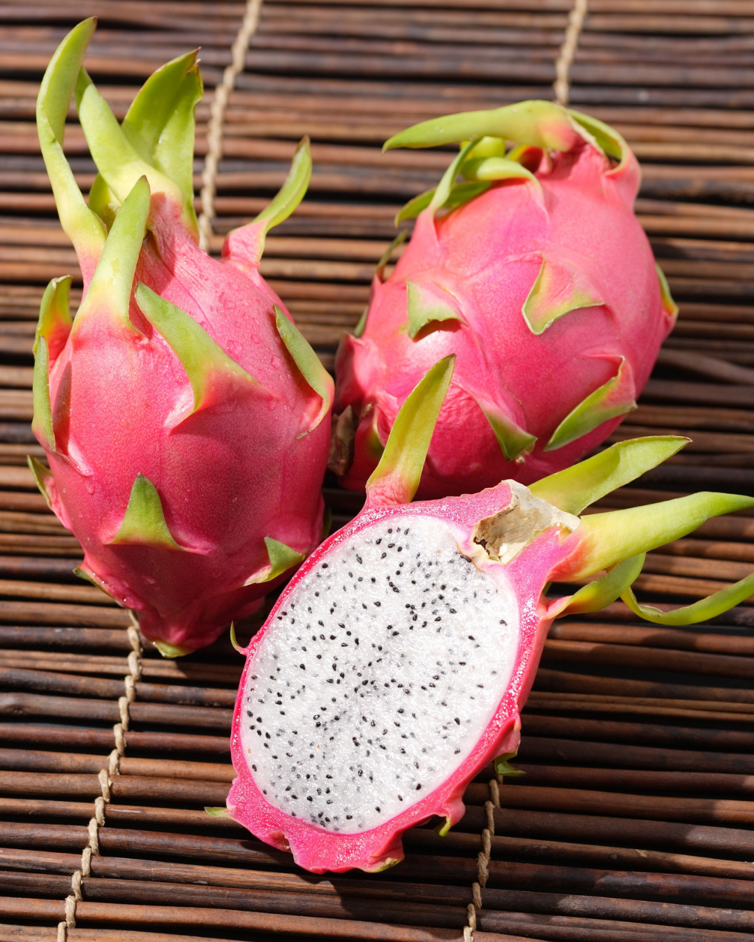 Freshly sliced dragon fruit showing bright pink skin and white flesh speckled with black seeds.